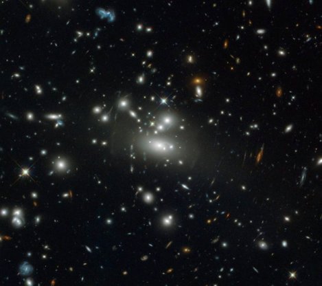 La masiva concentración de materia oscura y galaxias en el cúmulo Abell S1077 curva el espacio tiempo a su alrededor desviando la luz de galaxias lejanas hacia nosotros. Crédito: ESA.